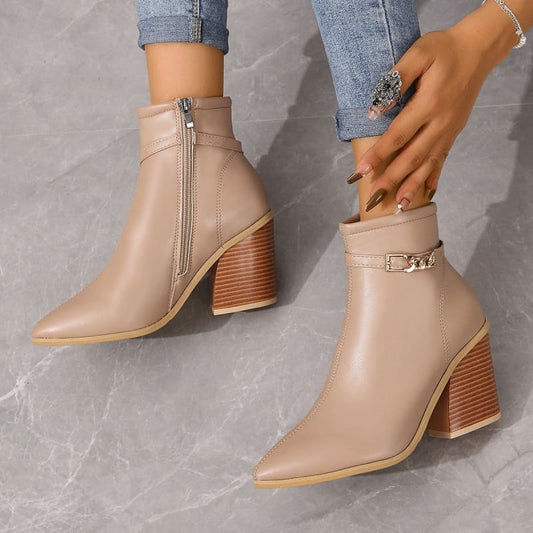 Pair of beige ankle boots with pointed toes and chunky wooden heels.