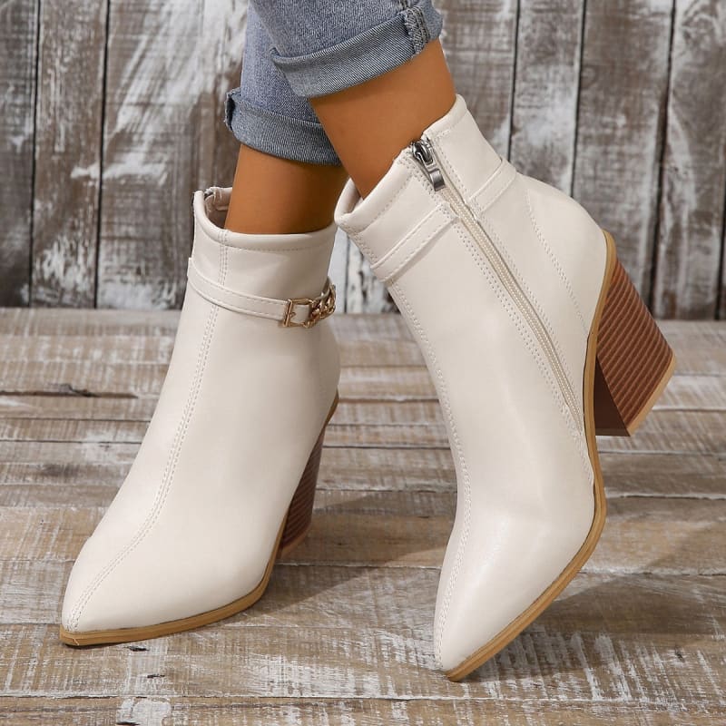 Pair of cream-colored ankle boots with pointed toes and wooden block heels.