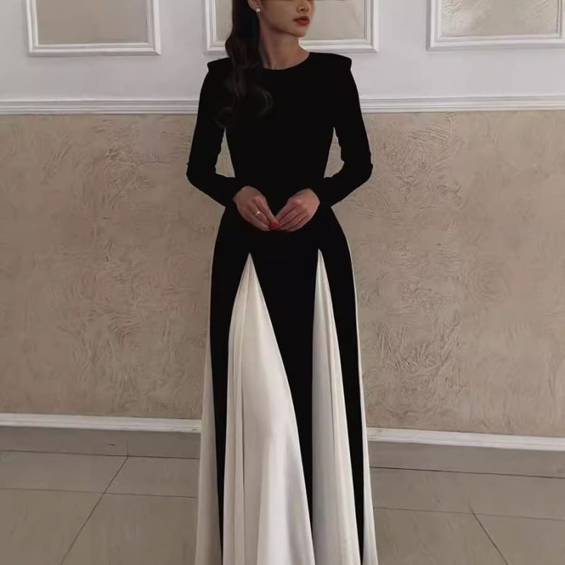 Long black dress with white panels in the skirt and fitted long sleeves.