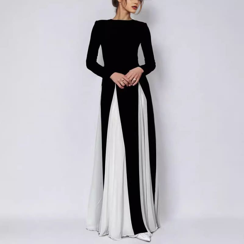 Long-sleeved black and white color-block maxi dress with a fitted bodice and flowing skirt.