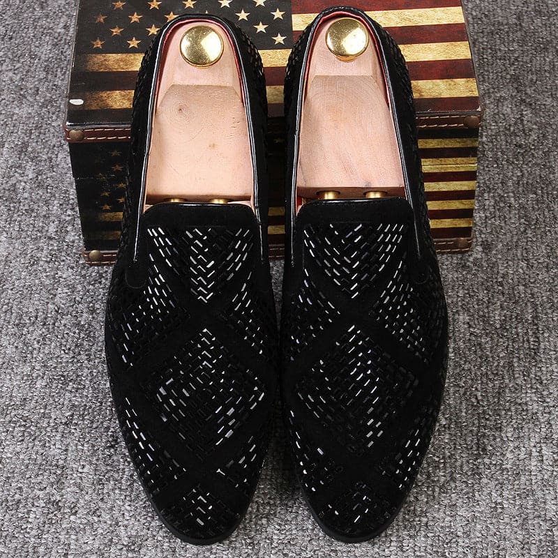 Pair of black leather loafers with intricate perforated pattern design.