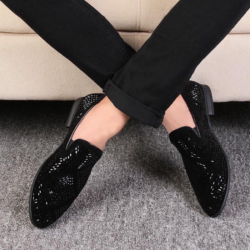 Pair of black patent leather loafers with decorative perforations.