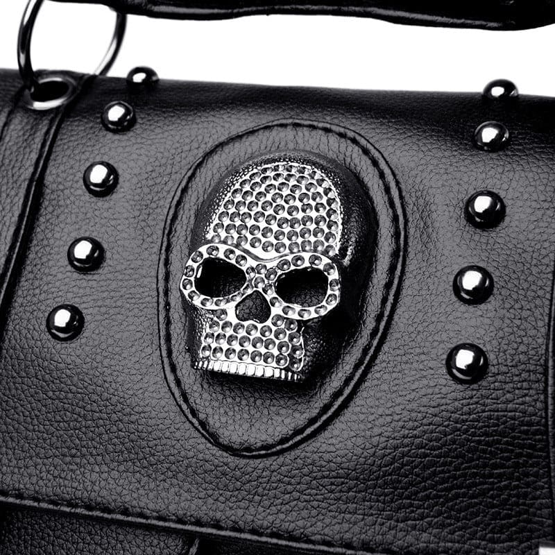 Silver skull-shaped ornament embedded in black leather, surrounded by metal studs.