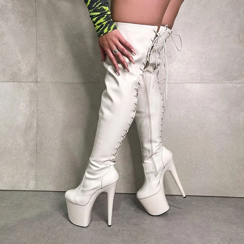 Thigh-high white platform boots with extremely high heels and lace-up detailing.