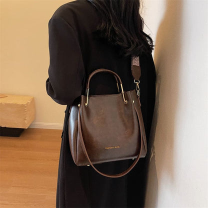 Brown leather handbag with dual handles and a shoulder strap.