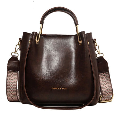 Dark brown leather handbag with gold hardware and a patterned shoulder strap.