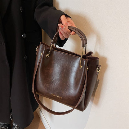 Brown leather handbag with dual handles and a shoulder strap.