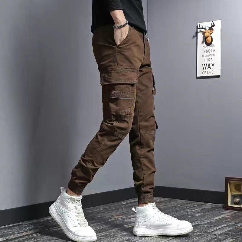 Brown cargo pants with multiple pockets worn with white high-top sneakers.