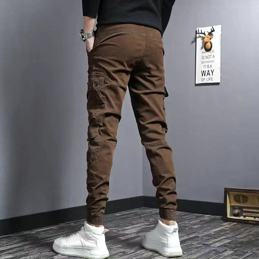 Brown cargo pants with multiple pockets worn with white high-top sneakers.