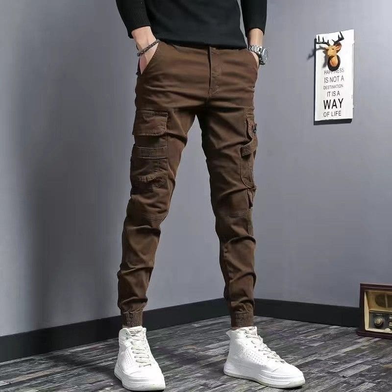 Brown cargo pants with multiple pockets worn with white high-top sneakers.