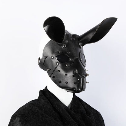 Black leather mask with rabbit-like ears and metal studs, worn over a dark suit collar.