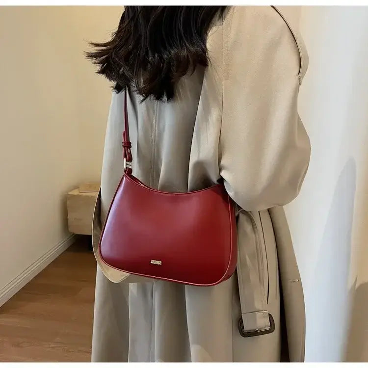 Burgundy leather shoulder bag crossbody with a chic curved silhouette and adjustable strap.