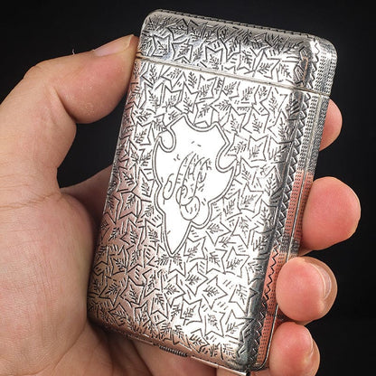 Ornately engraved silver cigarette case held in a hand.