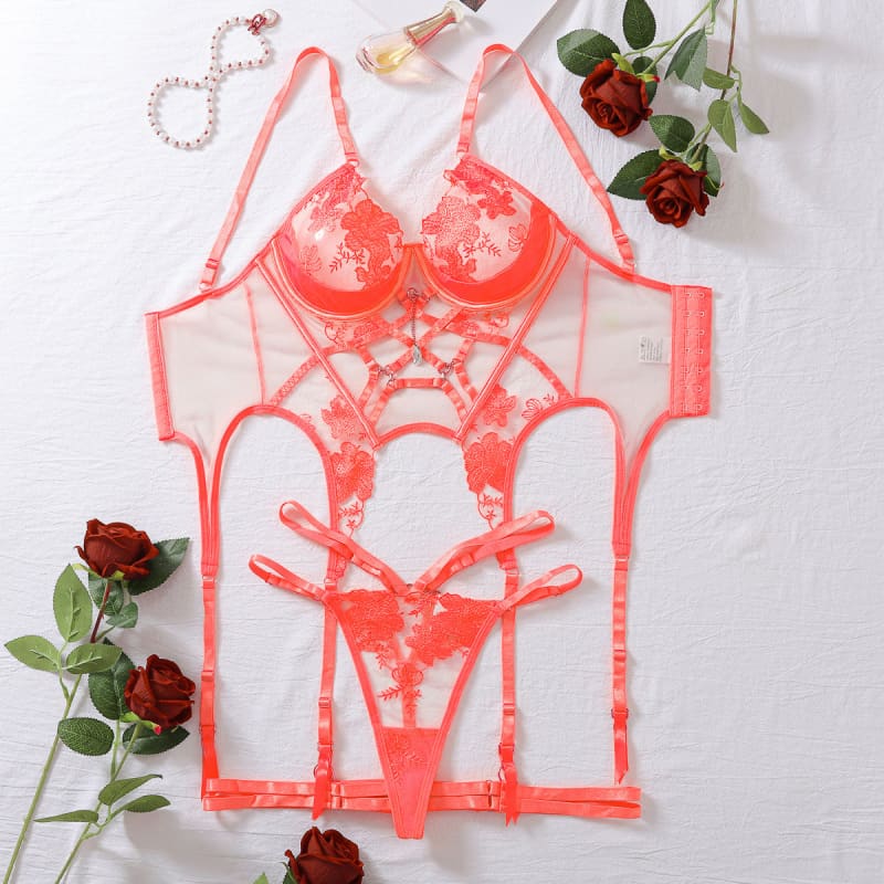 Coral-colored lace lingerie set with intricate strappy details.