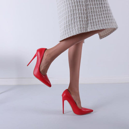 Bright red high-heeled stiletto shoes worn on a person’s feet.