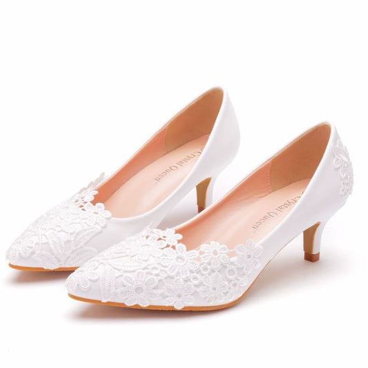 White lace kitten heel pumps with floral embellishments.