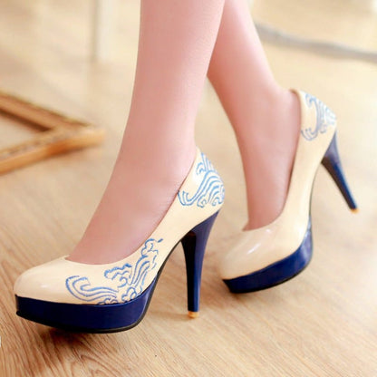 High-heeled platform pumps with cream-colored uppers featuring blue decorative patterns and navy blue soles and heels.