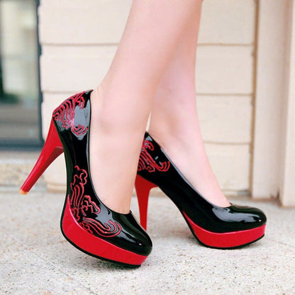 Stylish high heels with a black and red color scheme featuring decorative swirl patterns.