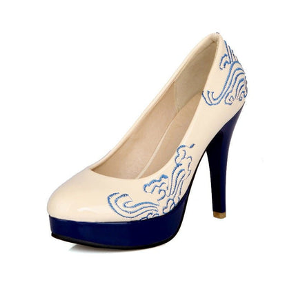 High-heeled pump shoe with cream-colored upper and blue embroidered pattern, featuring a navy blue platform sole and heel.