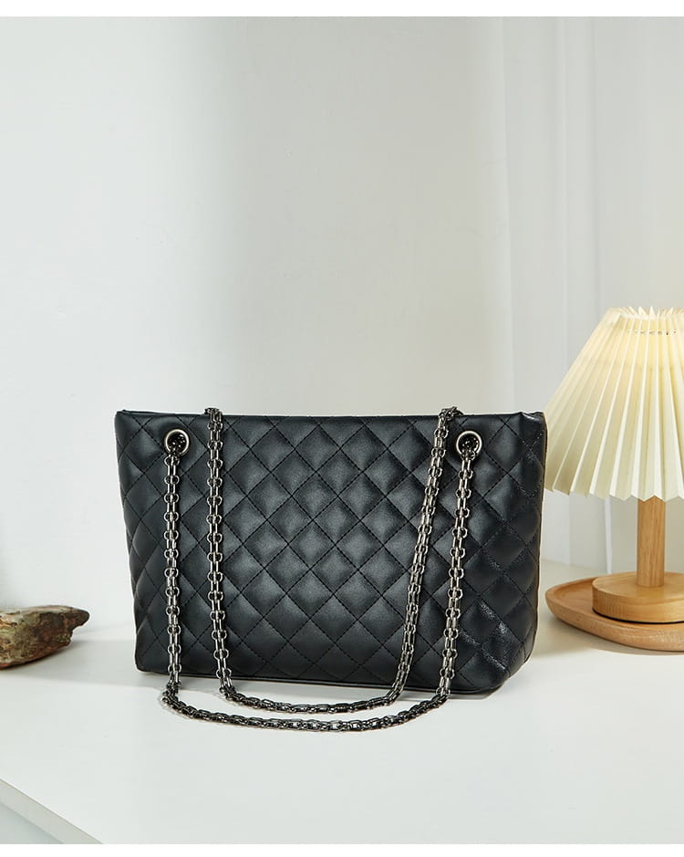 Black quilted leather handbag with shimmering chain strap and diamond plaid design.