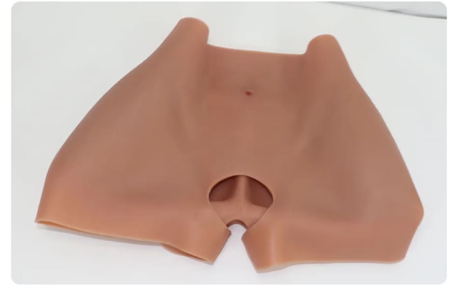 Flesh-colored silicone or rubber prosthetic with a circular opening in the center.