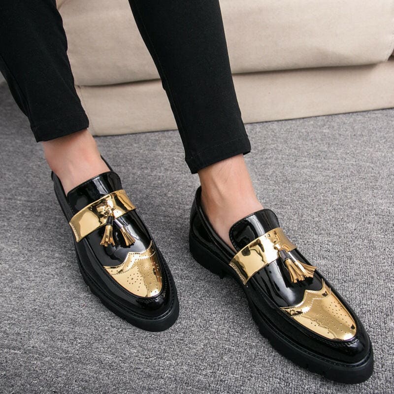 Stylish black and gold loafers with tassels worn on feet.