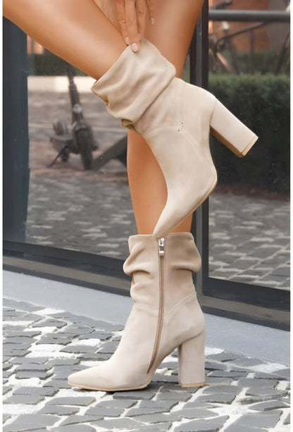 Cream-colored knee-high boots with chunky heels and side zippers.