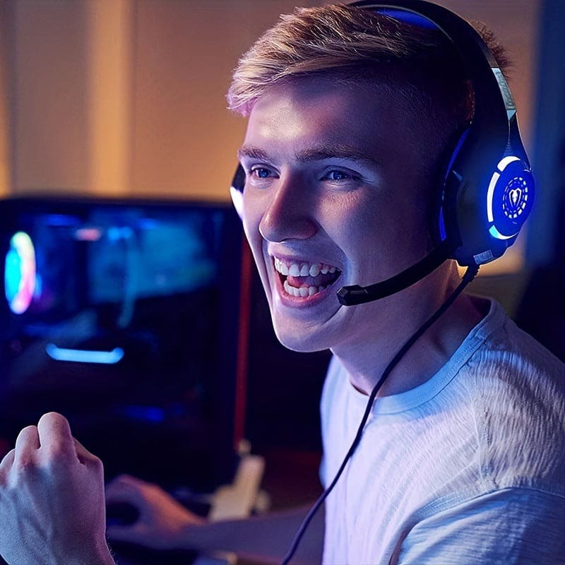 Enthusiastic young gamer wearing blue illuminated headphones with a microphone.