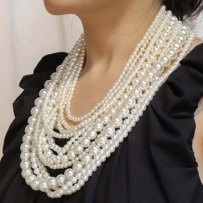 Multi-strand pearl necklace with varying sizes of pearls draped over a black garment.