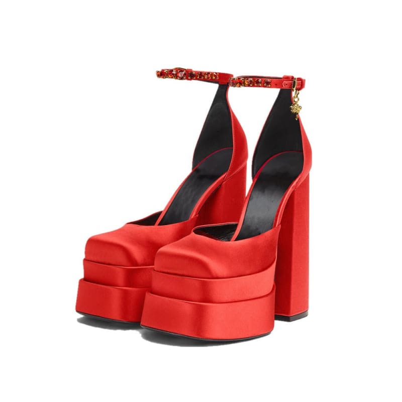 Pair of bright red platform high heels with ankle straps and chunky soles.