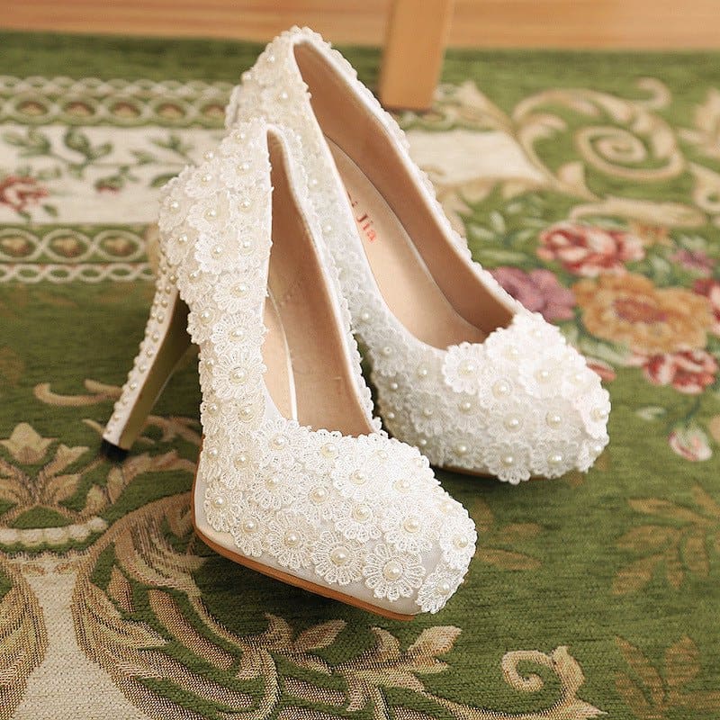 Pair of white high-heeled shoes adorned with sequins or beads.