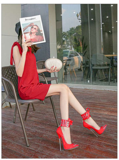 Woman in a red dress and high heels sitting on a chair, holding a magazine in front of her face.