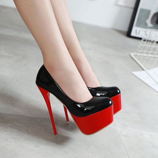 Pair of black and red high-heeled platform shoes with extremely tall stiletto heels.