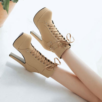 Pair of beige high-heeled ankle boots with laces and cutout heel design.