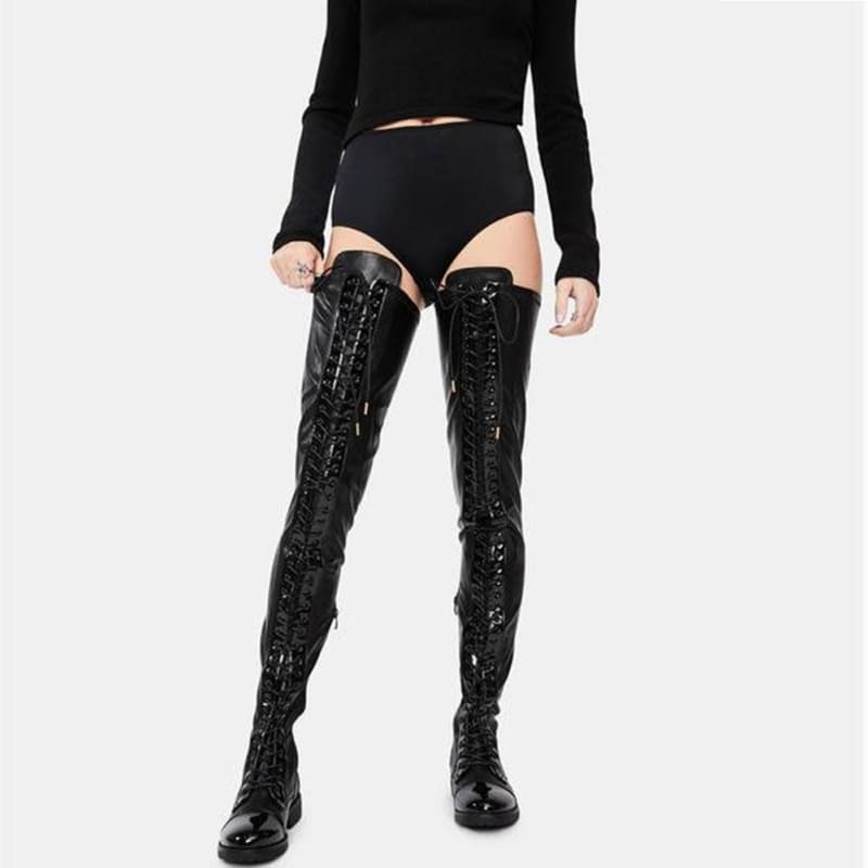 Pair of shiny black thigh-high lace-up boots worn by a person in dark clothing.