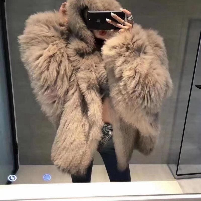 Fluffy beige faux fur coat being worn and photographed in a mirror.