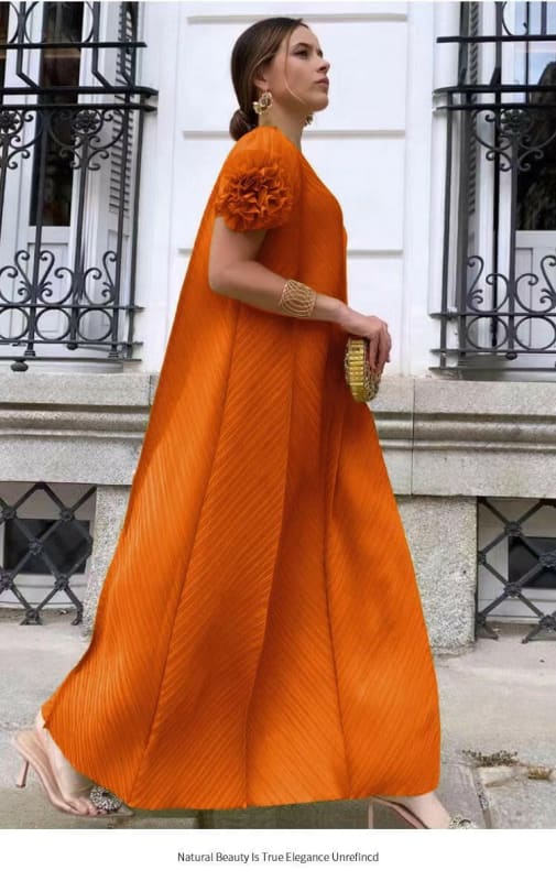 Vibrant orange floor-length gown with voluminous cape-like silhouette and floral shoulder detail.