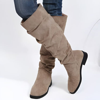 Tall beige suede boots with a slouchy shaft and flat heel.