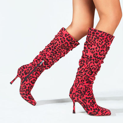 Pair of knee-high red and black leopard print boots with stiletto heels.