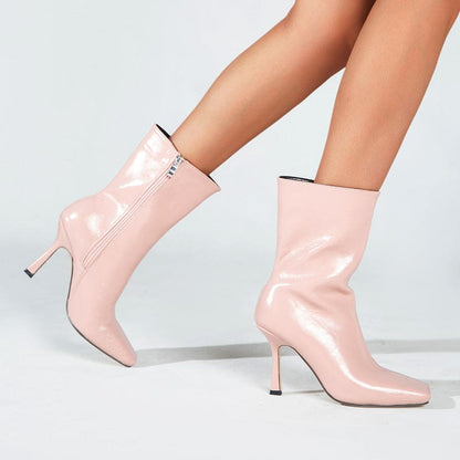 Pair of glossy pale pink high-heeled ankle boots.