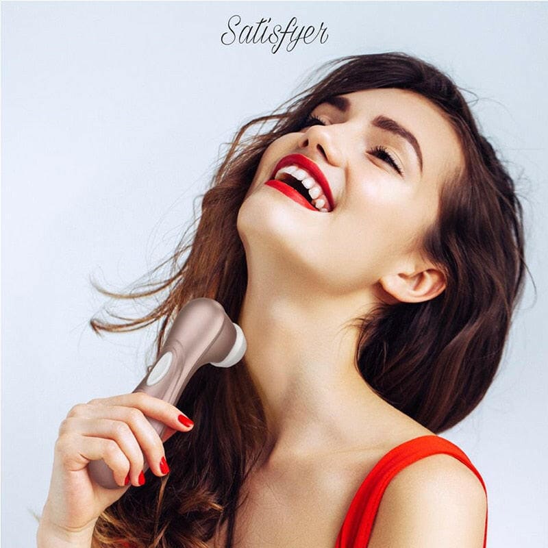 Woman with long dark hair laughing while holding a makeup brush.