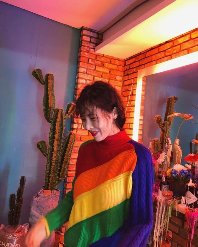 Rainbow-striped sweater worn by a person with dark hair.