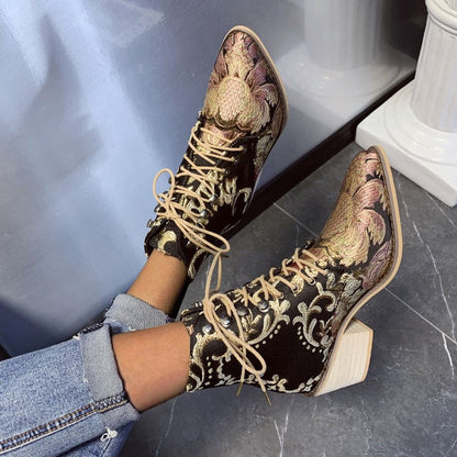 Ornate high-heeled ankle boots with intricate floral brocade pattern and lace-up front.