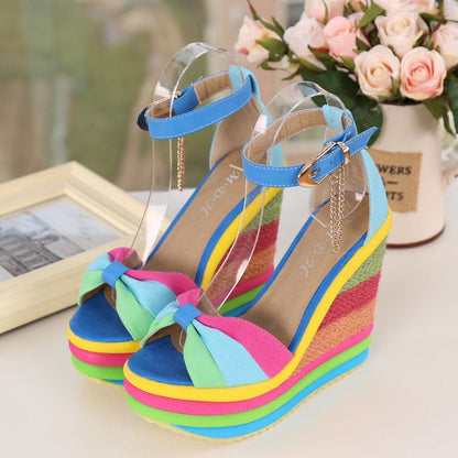 Colorful rainbow-striped platform wedge sandals with an ankle strap and bow detail.