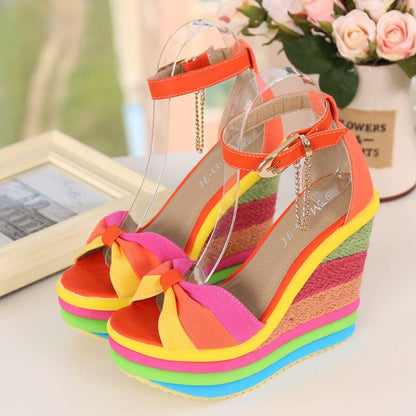 Colorful rainbow-striped wedge sandals with ankle straps and bow details.