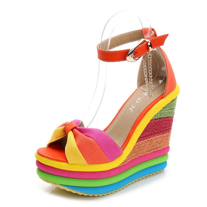 Colorful rainbow-striped platform wedge sandal with an ankle strap and bow detail.