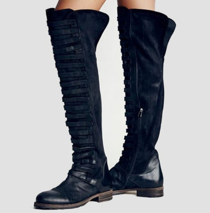 Pair of black over-the-knee boots with side zippers and decorative straps.