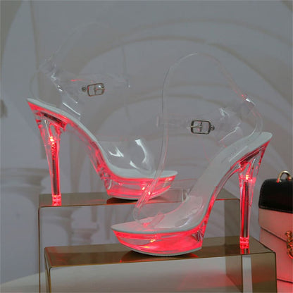 Clear high-heeled sandals with glowing neon pink accents.