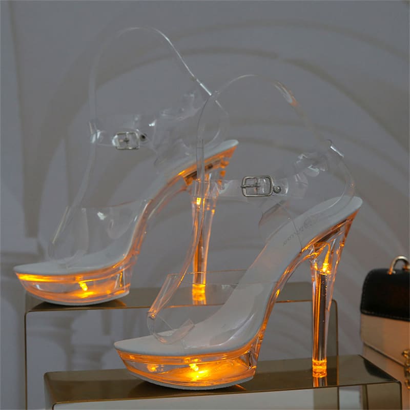 Clear high-heeled platform sandals with illuminated orange bases and stiletto heels.