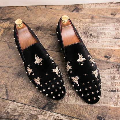 Pair of black suede loafers decorated with gold bee motifs and studded embellishments.